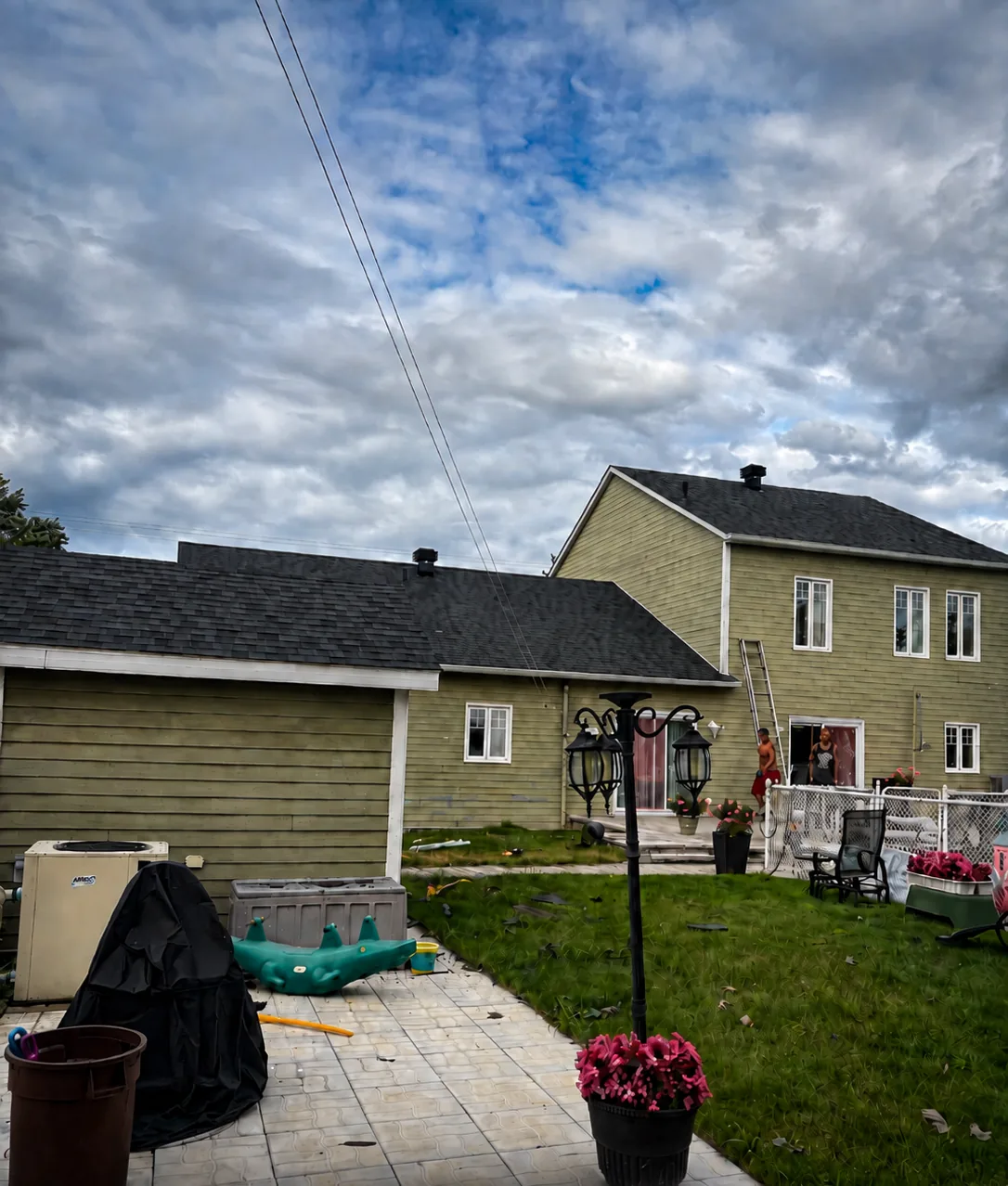 Maison à revêtement vert avec une toiture neuve en bardeau noir, équipe sur place