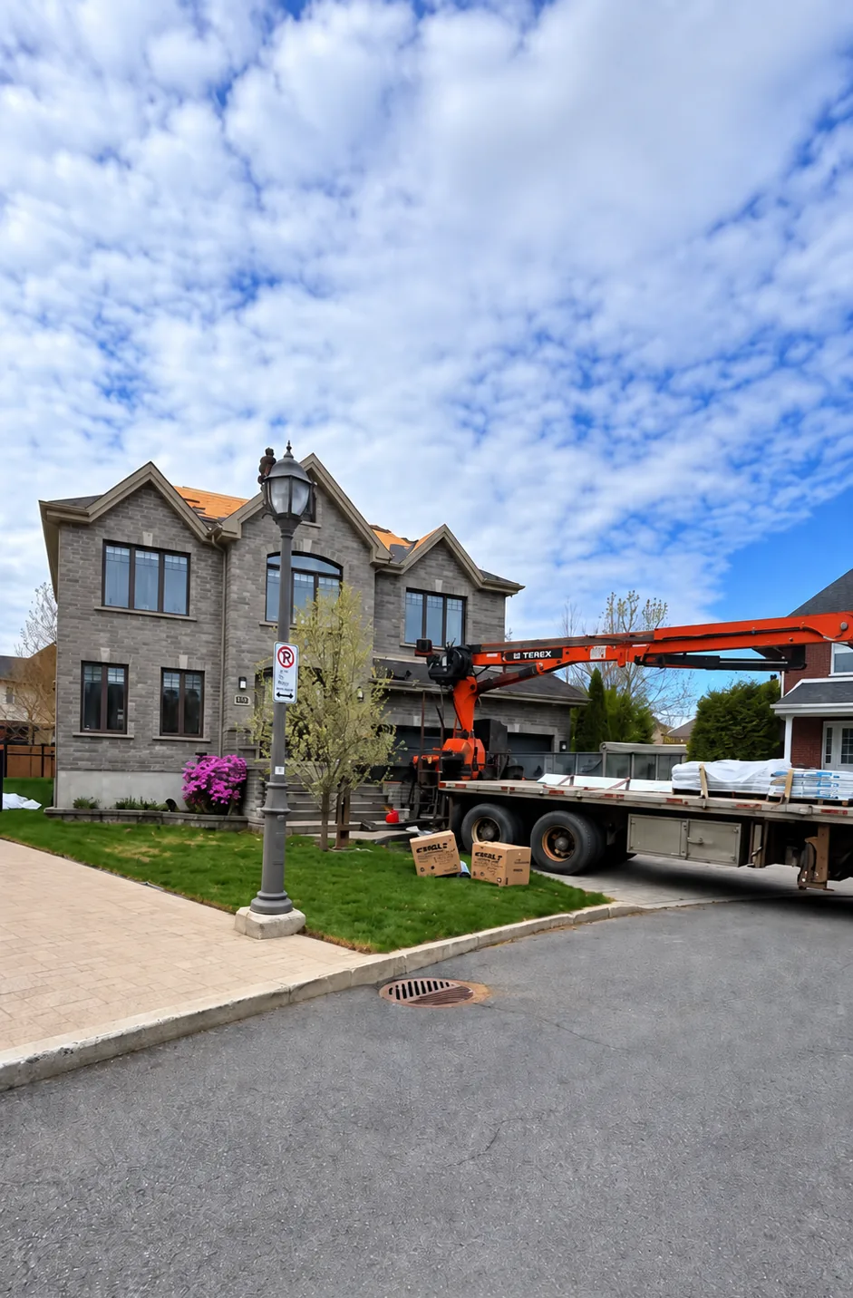 Camion-grue livrant les bardeaux sur le toit d'une maison en pierre